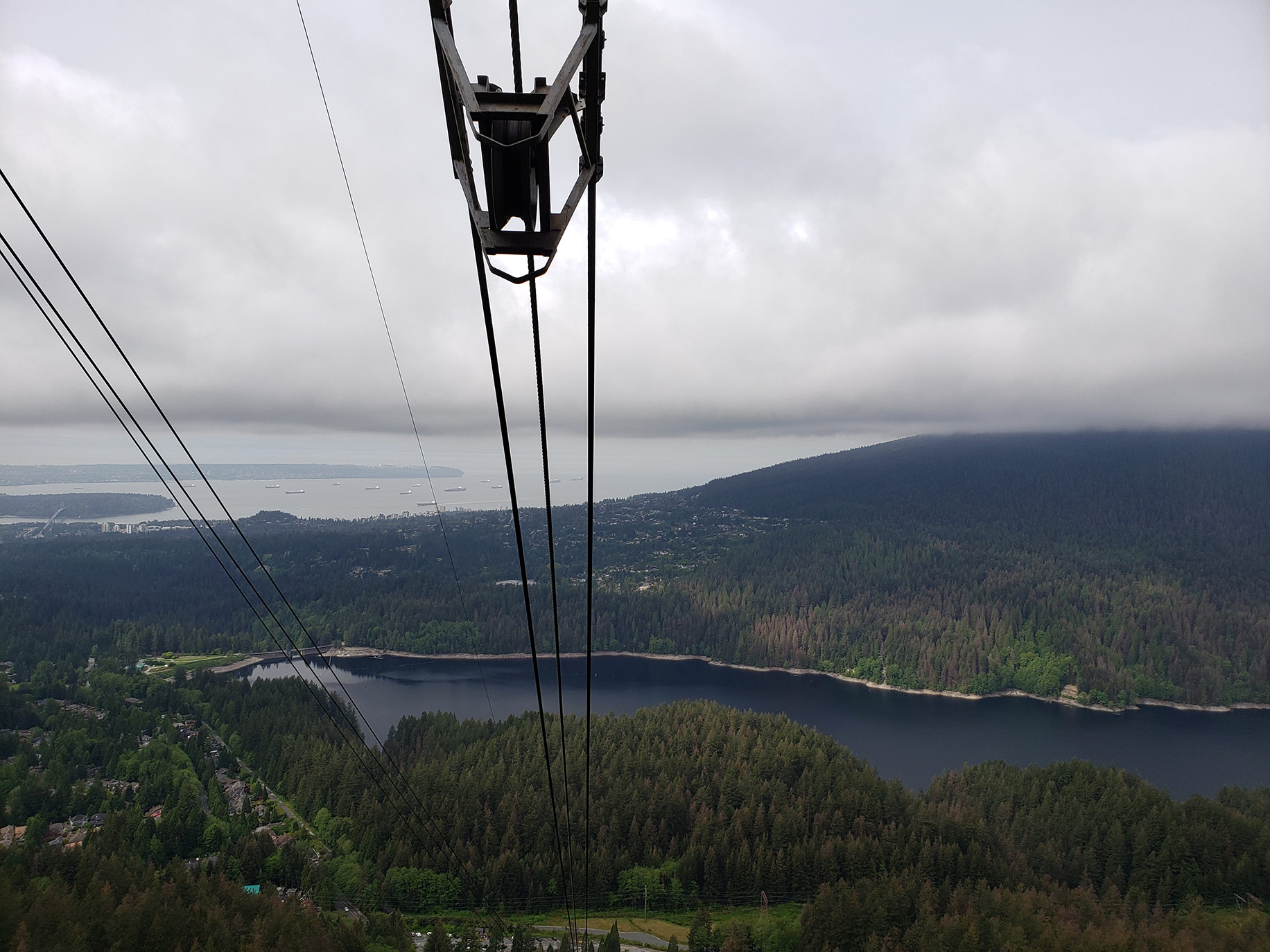 A view from the Grouse Mountain gondola showing the Capilano Lake dam, Stanley Park, and the Lions Gate Bridge.